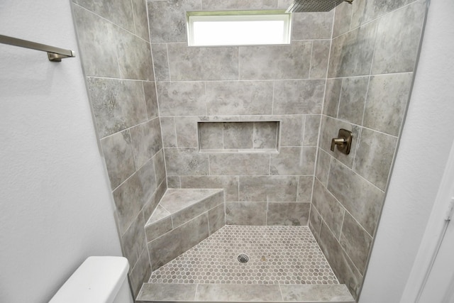 bathroom featuring a tile shower and toilet