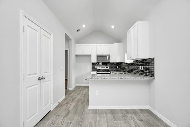 kitchen featuring kitchen peninsula, stainless steel appliances, sink, light stone countertops, and white cabinetry