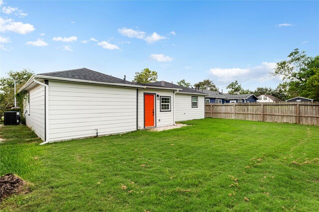 back of property with a yard and central AC unit