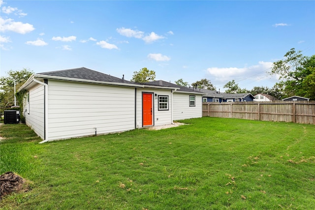 rear view of house featuring a lawn, cooling unit, and fence