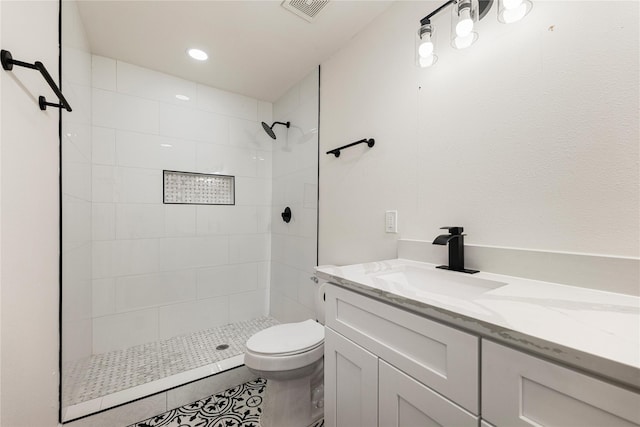 bathroom with visible vents, vanity, toilet, and tiled shower