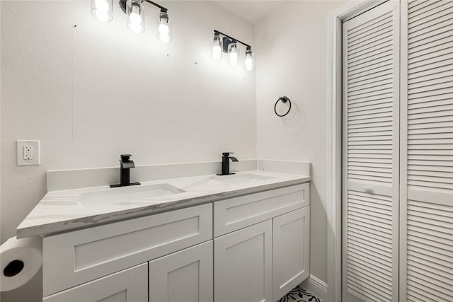 bathroom featuring double vanity, a closet, and a sink