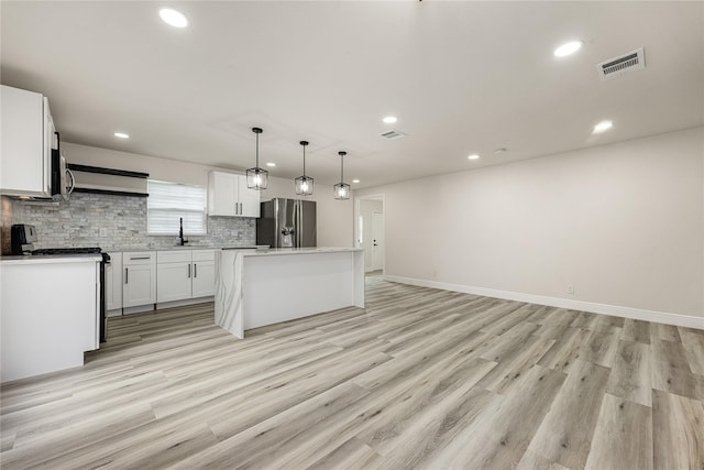 kitchen featuring light wood finished floors, tasteful backsplash, visible vents, appliances with stainless steel finishes, and white cabinetry