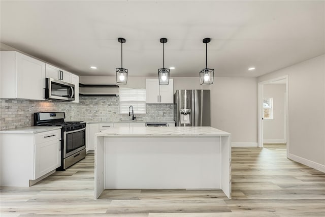 kitchen featuring appliances with stainless steel finishes, white cabinets, a sink, and a center island