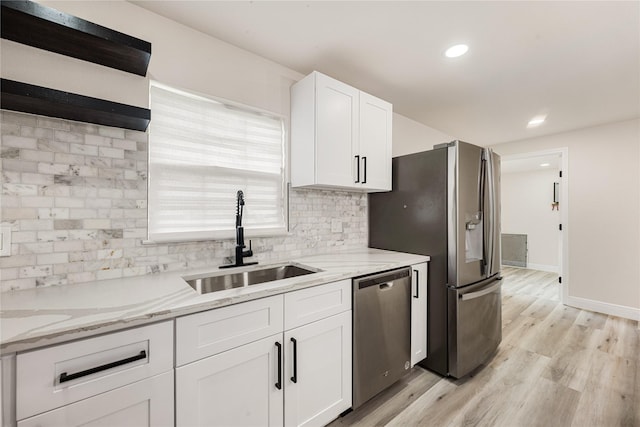 kitchen with light stone countertops, sink, white cabinetry, and stainless steel appliances