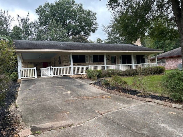 ranch-style home with a carport, covered porch, and concrete driveway