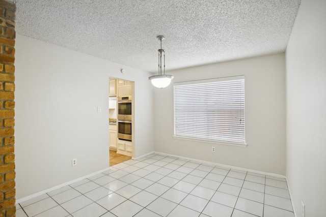 empty room featuring a textured ceiling and light tile patterned flooring