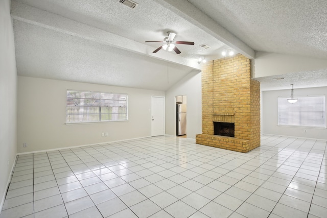 unfurnished living room featuring ceiling fan, a textured ceiling, a brick fireplace, and plenty of natural light