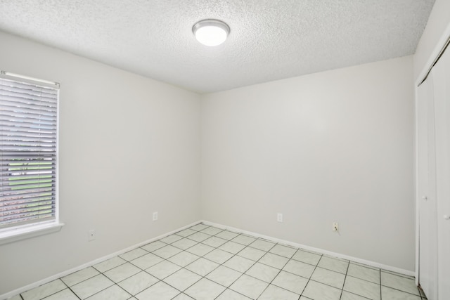 spare room with a textured ceiling and light tile patterned floors