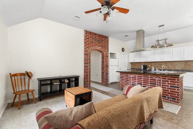 tiled living room featuring ceiling fan, lofted ceiling, and sink