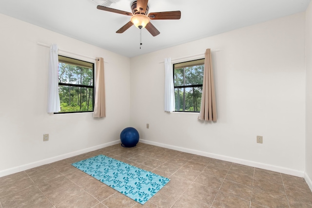 empty room featuring ceiling fan, light tile patterned flooring, and a healthy amount of sunlight