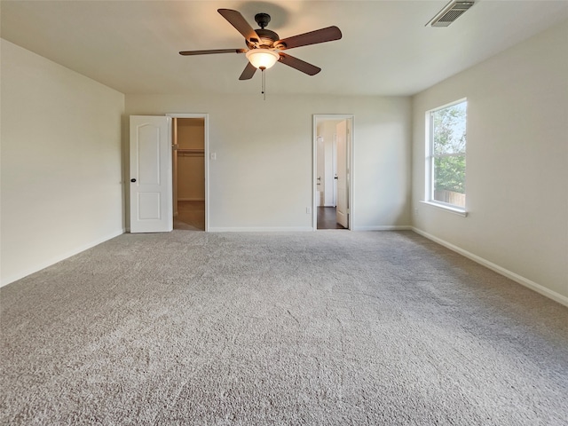 interior space with ceiling fan, a closet, carpet, and a walk in closet