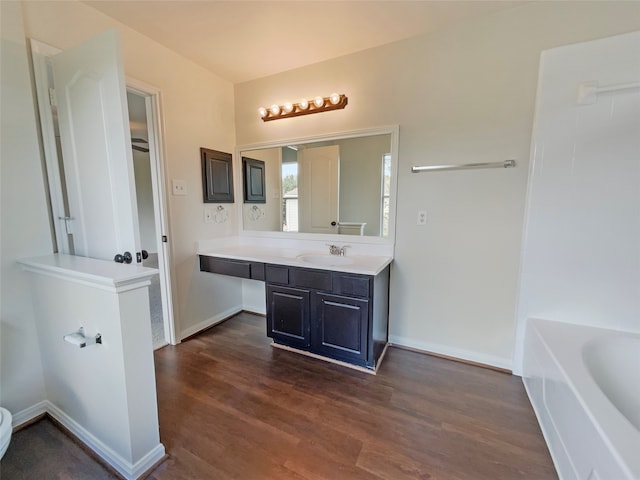 bathroom featuring wood-type flooring, vanity, and a tub