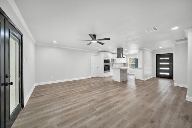 unfurnished living room featuring light wood-type flooring, crown molding, and ceiling fan