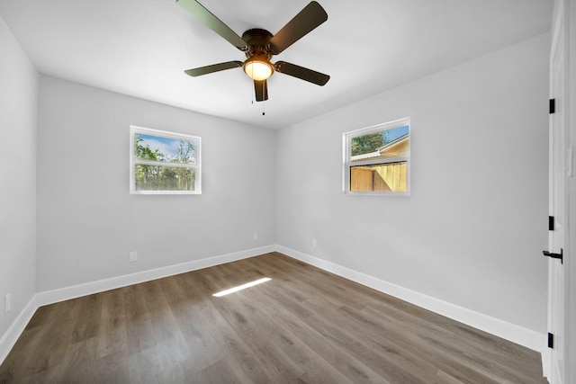 empty room featuring ceiling fan, hardwood / wood-style flooring, and a wealth of natural light