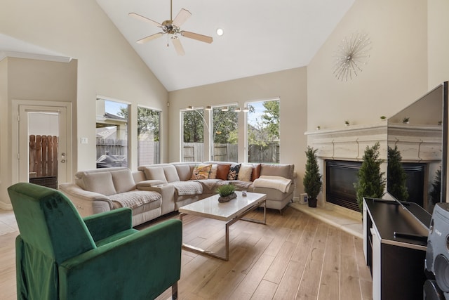 living room with light hardwood / wood-style flooring, ceiling fan, a high end fireplace, and high vaulted ceiling