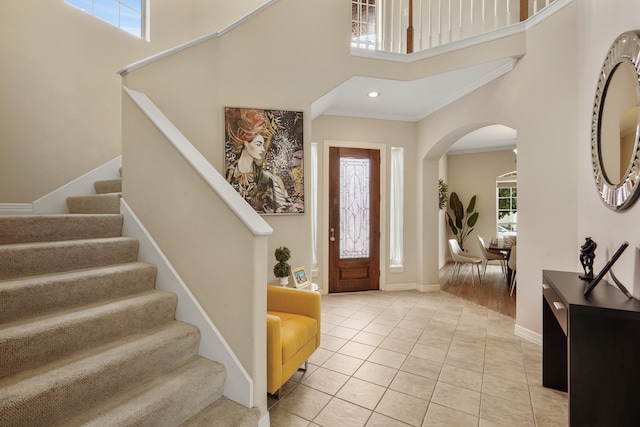 tiled foyer entrance featuring ornamental molding and a high ceiling