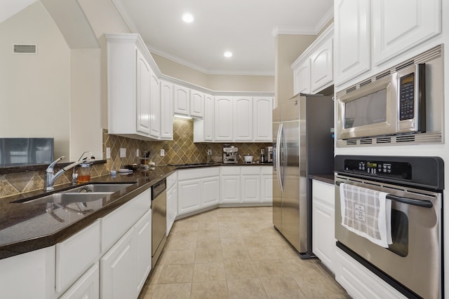 kitchen featuring appliances with stainless steel finishes, decorative backsplash, white cabinets, light tile patterned floors, and sink