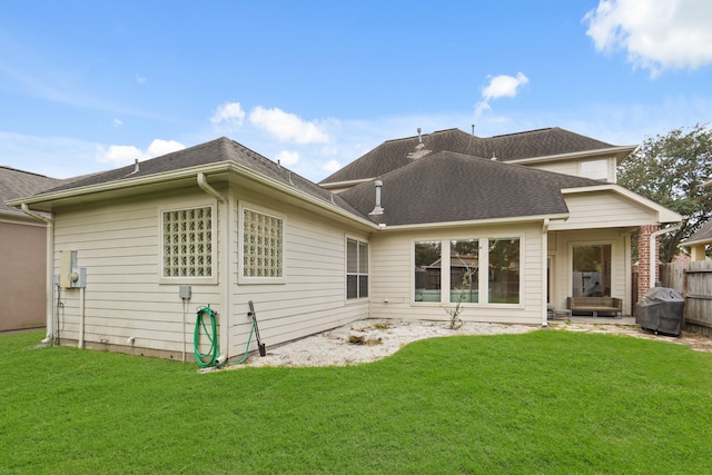 rear view of house featuring a lawn and a patio