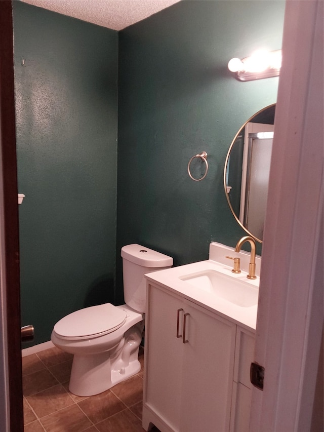 bathroom with tile patterned flooring, a textured ceiling, vanity, and toilet