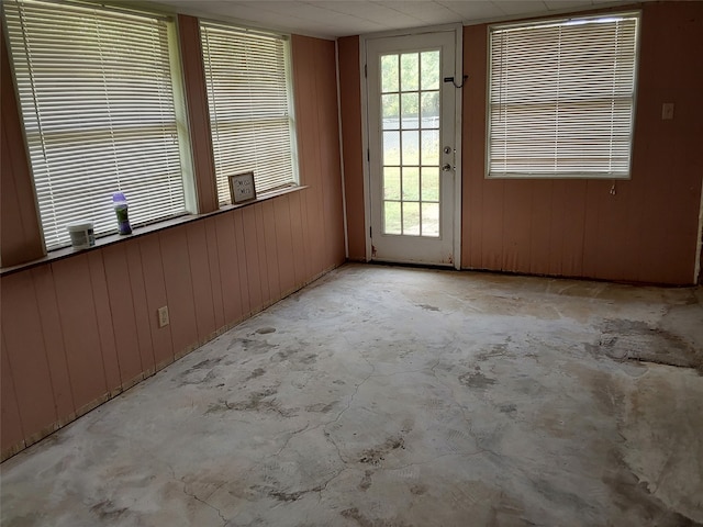 unfurnished room featuring wooden walls