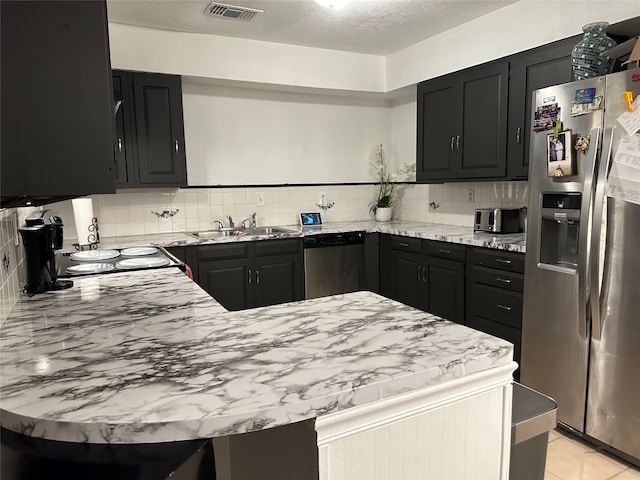 kitchen with a textured ceiling, stainless steel appliances, sink, and decorative backsplash