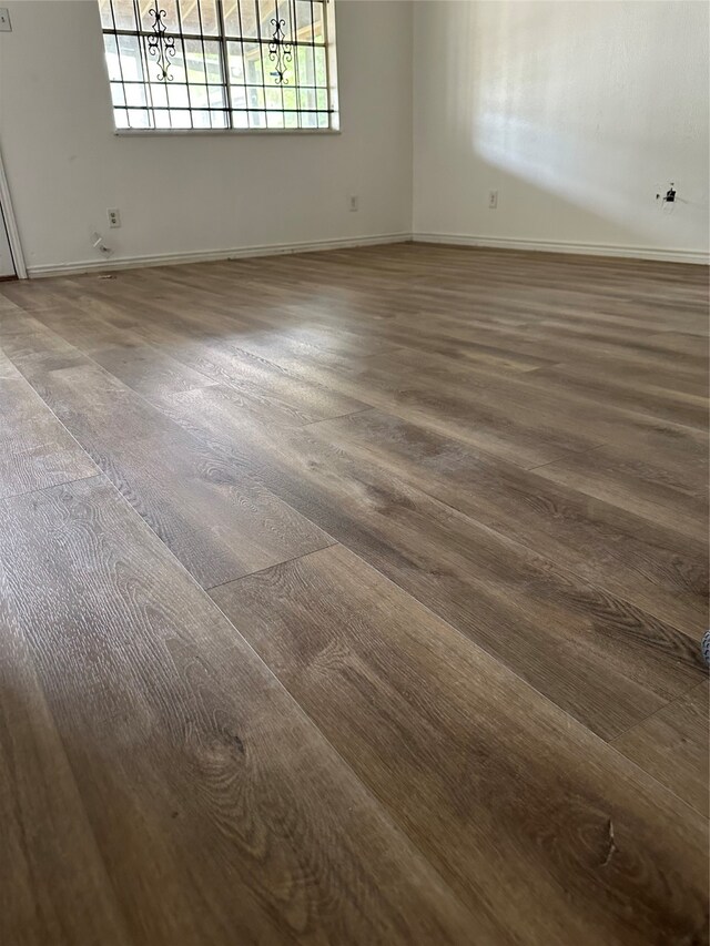 empty room with a notable chandelier and dark hardwood / wood-style flooring