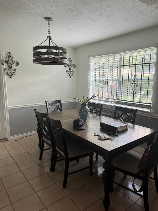 tiled dining room featuring a notable chandelier and a textured ceiling