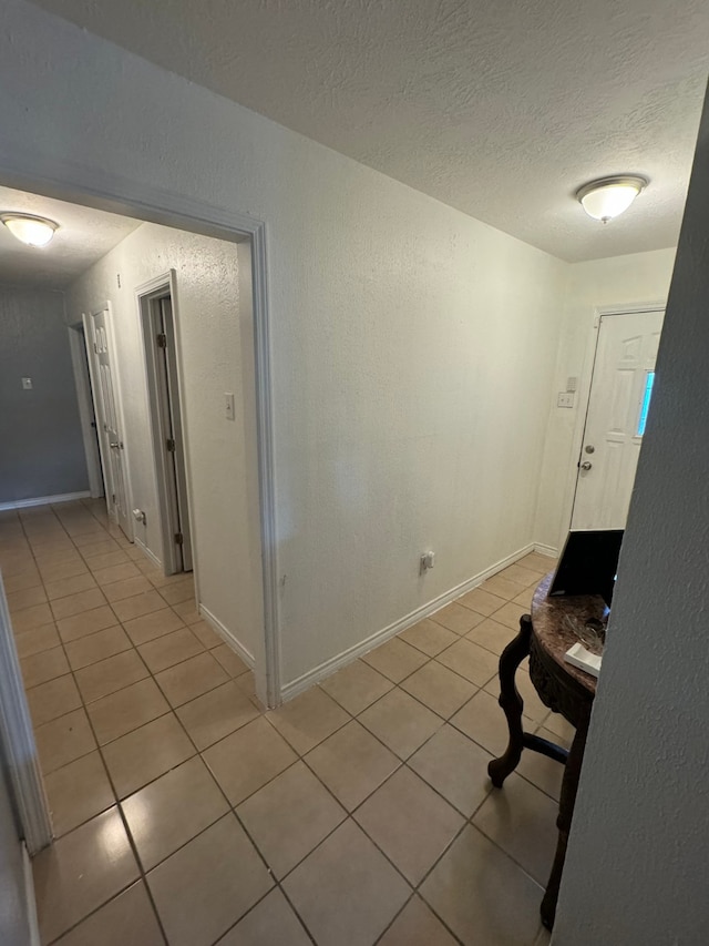 hall featuring light tile patterned flooring and a textured ceiling