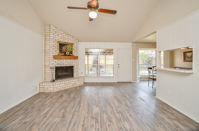 unfurnished living room featuring vaulted ceiling, a fireplace, ceiling fan, and wood-type flooring