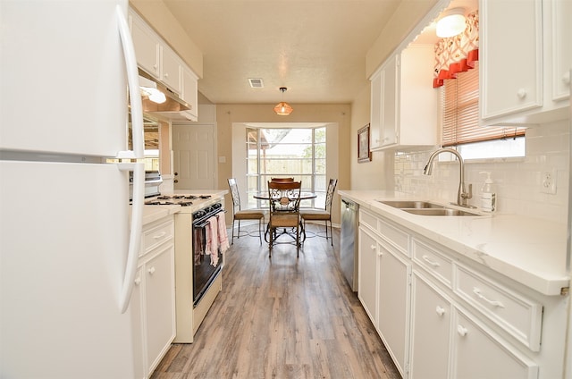 kitchen featuring white appliances, decorative backsplash, light wood-type flooring, white cabinetry, and sink