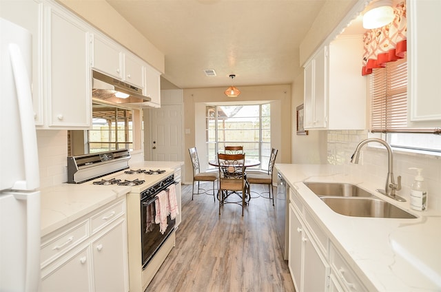 kitchen with white appliances, white cabinets, light stone countertops, and sink