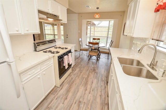 kitchen with white appliances, hanging light fixtures, white cabinets, and sink