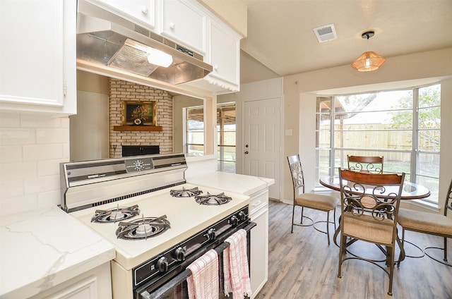 kitchen with hanging light fixtures, white cabinetry, light stone countertops, and white gas range oven