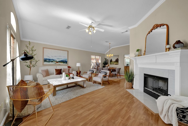 living room featuring a tiled fireplace, light hardwood / wood-style flooring, ornamental molding, and ceiling fan