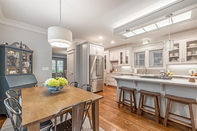 dining area with sink, crown molding, and light hardwood / wood-style flooring