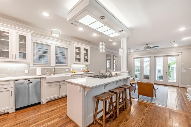 kitchen featuring pendant lighting, sink, appliances with stainless steel finishes, a center island, and white cabinets