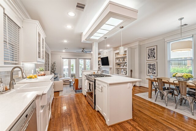 kitchen with sink, white cabinetry, hanging light fixtures, a kitchen island, and stainless steel appliances