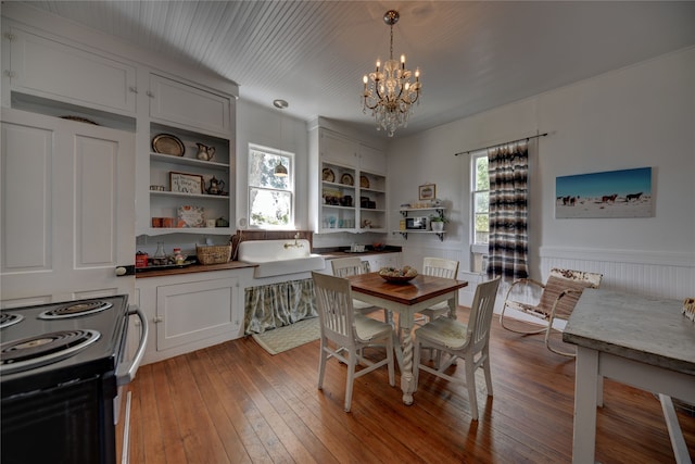 dining area with an inviting chandelier, built in shelves, wood walls, and light hardwood / wood-style floors