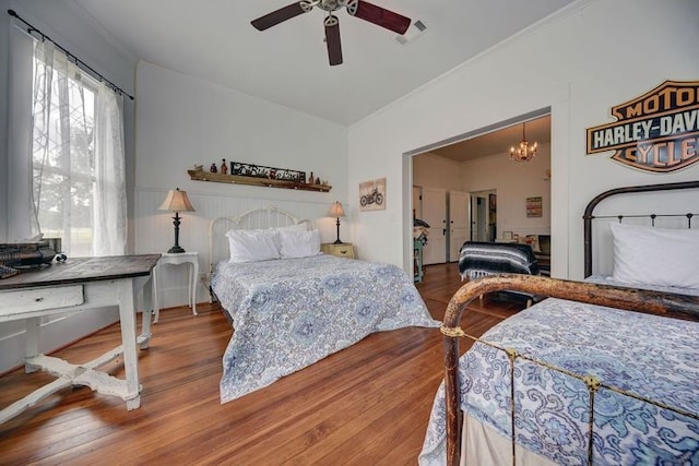 bedroom featuring wood-type flooring and ceiling fan with notable chandelier