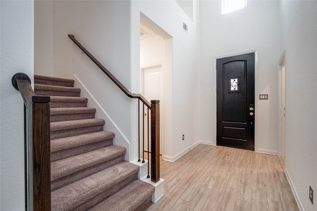 entryway with a towering ceiling and light hardwood / wood-style floors