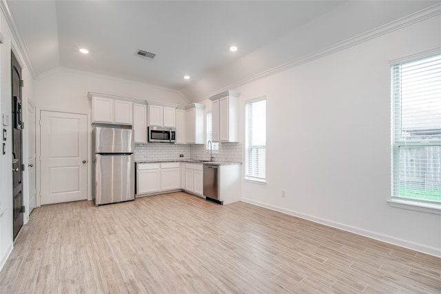 kitchen featuring light hardwood / wood-style floors, white cabinets, lofted ceiling, stainless steel appliances, and crown molding