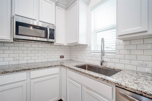 kitchen with appliances with stainless steel finishes, sink, and white cabinets