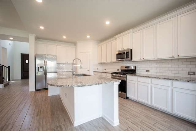 kitchen featuring light hardwood / wood-style floors, backsplash, stainless steel appliances, a kitchen island with sink, and sink