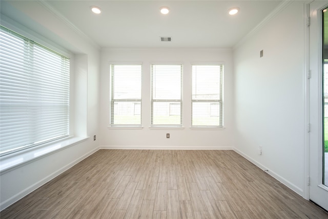 empty room with light wood-type flooring, a healthy amount of sunlight, and ornamental molding