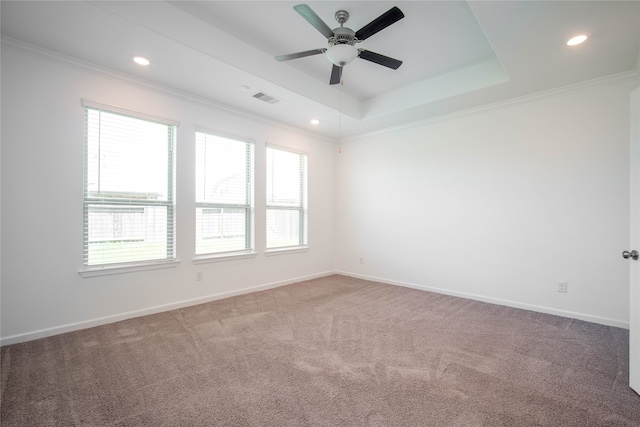 carpeted empty room with ceiling fan, a tray ceiling, and ornamental molding