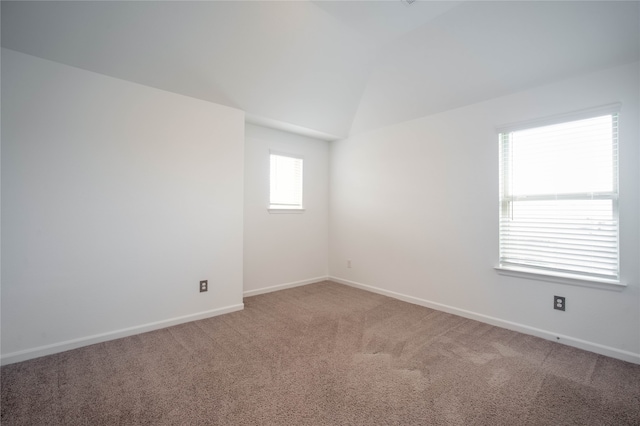 carpeted spare room with lofted ceiling