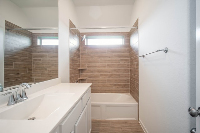 bathroom with a wealth of natural light, wood-type flooring, tiled shower / bath combo, and vanity