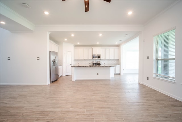 kitchen with ceiling fan, a kitchen island with sink, stainless steel appliances, and a wealth of natural light