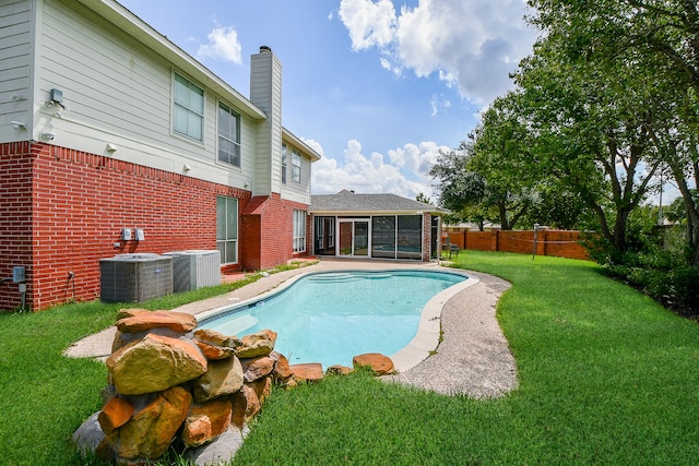 view of swimming pool featuring a lawn, cooling unit, and a sunroom